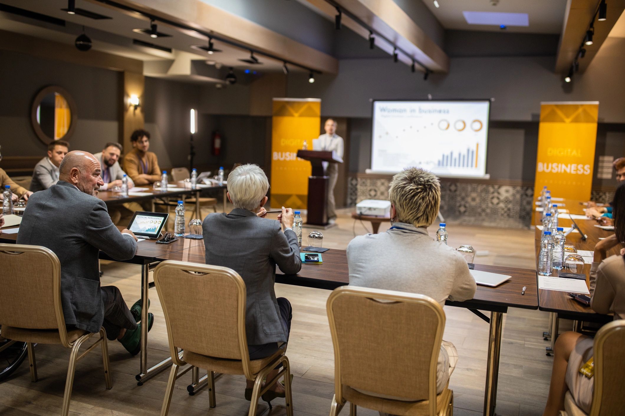 Business conference participants listening to a young woman's speech